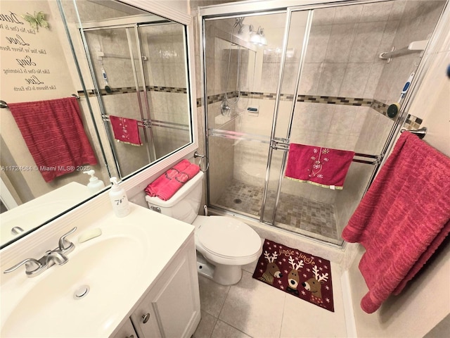 bathroom with toilet, vanity, tile patterned floors, and a shower with door