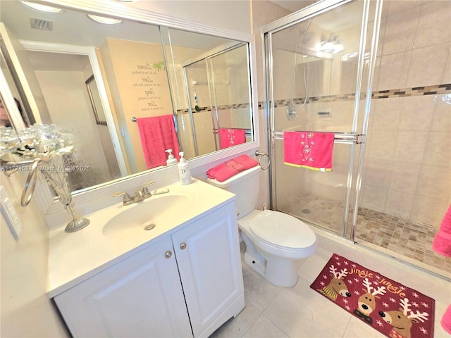 bathroom featuring tile patterned flooring, vanity, toilet, and a shower with shower door