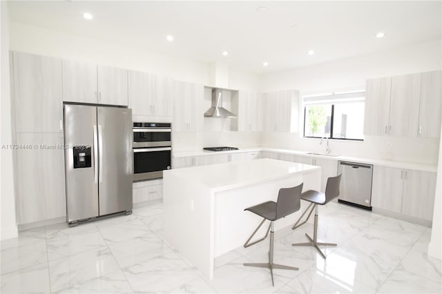 kitchen featuring sink, a breakfast bar area, a center island, stainless steel appliances, and wall chimney range hood