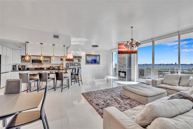 living room with visible vents, an inviting chandelier, a water view, and light tile patterned floors