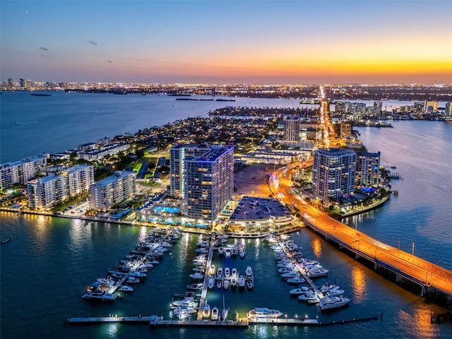aerial view at dusk featuring a city view and a water view
