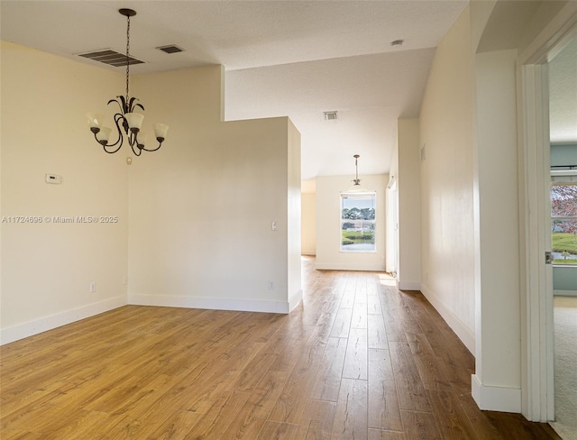 unfurnished room featuring hardwood / wood-style flooring and an inviting chandelier