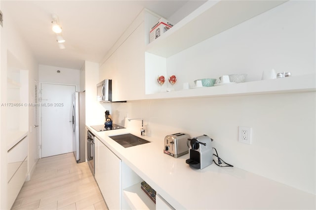 kitchen featuring appliances with stainless steel finishes, light hardwood / wood-style flooring, white cabinetry, and sink