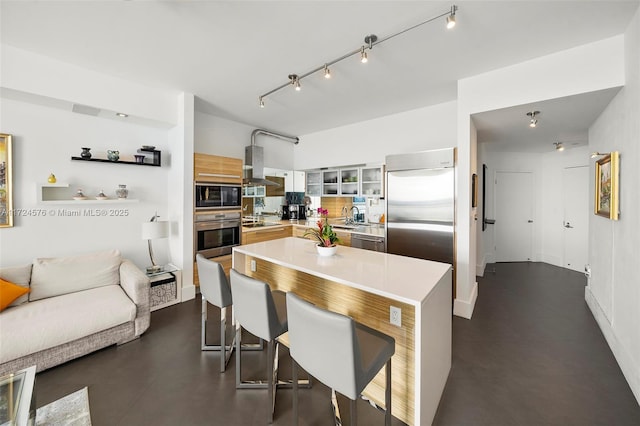 kitchen featuring a center island, black appliances, extractor fan, a kitchen breakfast bar, and sink