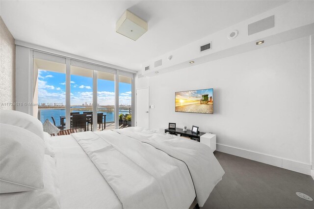 bedroom featuring a water view, access to outside, and floor to ceiling windows