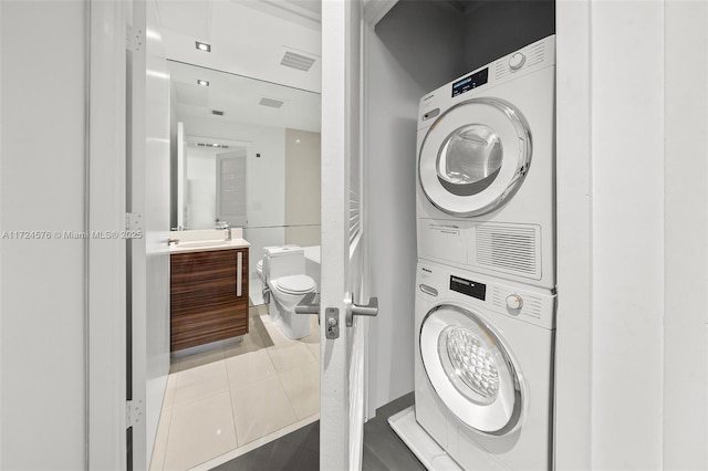 laundry area featuring tile patterned floors and stacked washer / drying machine