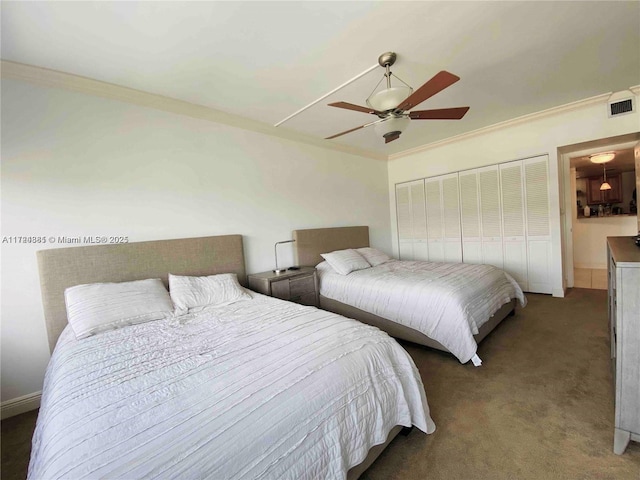 bedroom with dark colored carpet, ceiling fan, crown molding, and a closet