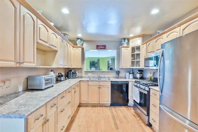 kitchen with light stone countertops, light brown cabinetry, stainless steel appliances, sink, and light hardwood / wood-style flooring