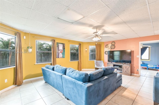 tiled living room with ceiling fan and a drop ceiling