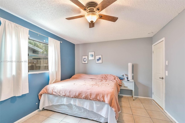 bedroom featuring ceiling fan, light tile patterned floors, and a textured ceiling