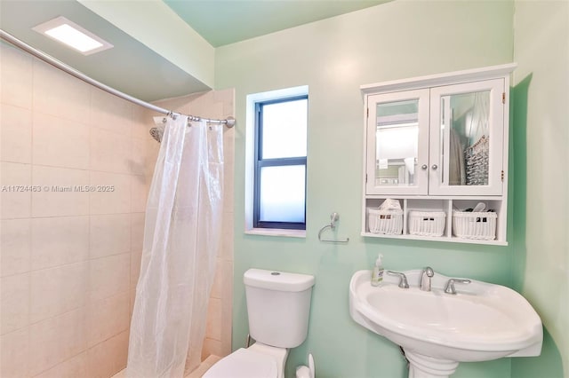 bathroom featuring a shower with shower curtain, toilet, and sink