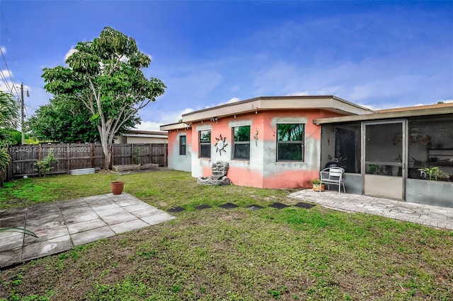 back of property featuring a yard, a patio area, and a sunroom