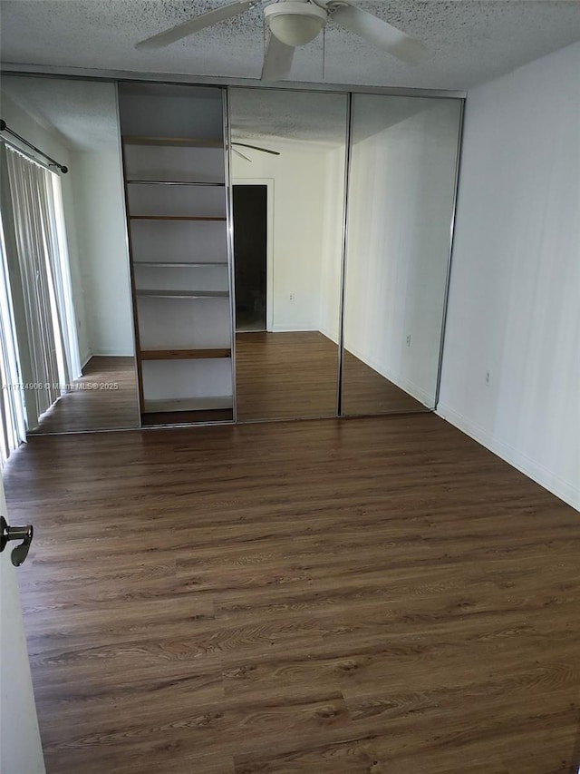 unfurnished bedroom featuring a textured ceiling, ceiling fan, a closet, and dark hardwood / wood-style floors