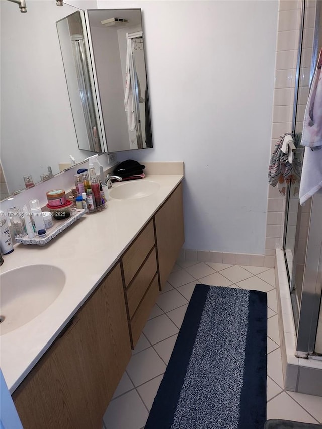 bathroom with a shower with shower door, tile patterned floors, and vanity