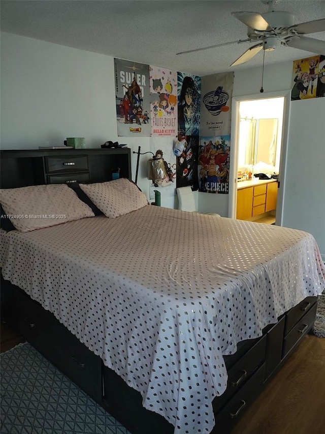 bedroom with ceiling fan, ensuite bath, dark hardwood / wood-style floors, and a textured ceiling