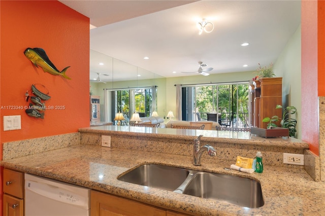 kitchen featuring light stone counters, ceiling fan, dishwasher, and sink