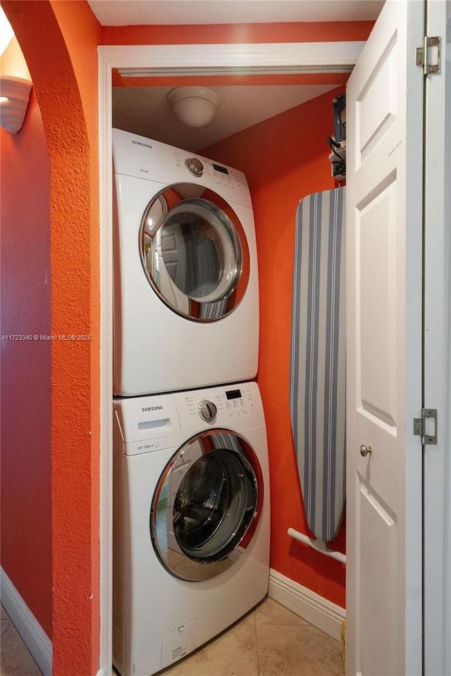 laundry area featuring light tile patterned floors and stacked washer and dryer