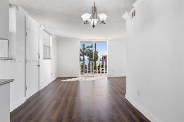 unfurnished room with dark hardwood / wood-style flooring, a textured ceiling, a chandelier, and expansive windows