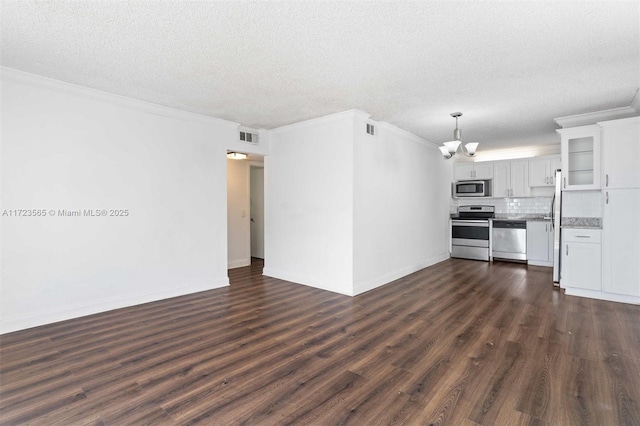 unfurnished living room with dark wood-type flooring, a textured ceiling, ornamental molding, and a chandelier