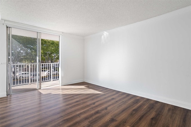 empty room featuring a wall of windows, dark hardwood / wood-style flooring, and a textured ceiling