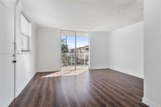 empty room with a wall of windows, a textured ceiling, and dark hardwood / wood-style floors