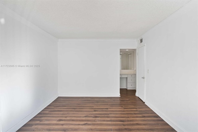 unfurnished room featuring dark wood-type flooring and a textured ceiling