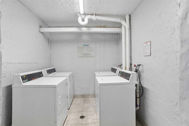 washroom with separate washer and dryer, light tile patterned flooring, and a textured ceiling