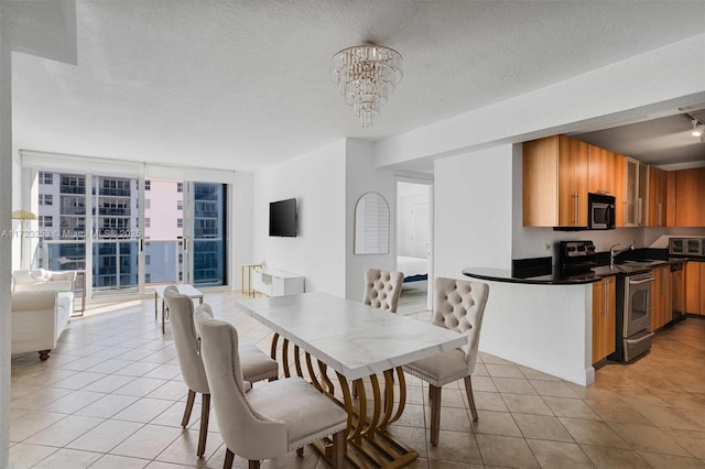 dining space with an inviting chandelier, light tile patterned floors, floor to ceiling windows, and a textured ceiling