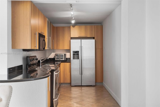 kitchen with appliances with stainless steel finishes, rail lighting, and light tile patterned floors