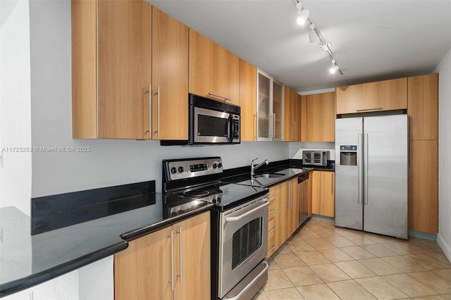 kitchen featuring light tile patterned flooring, appliances with stainless steel finishes, sink, and dark stone counters