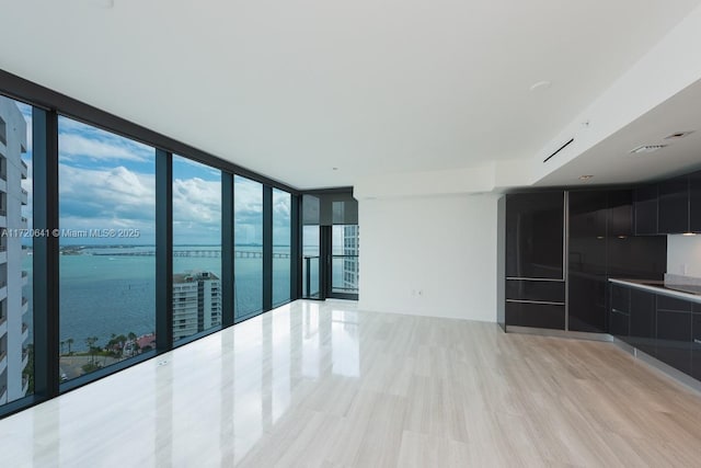 unfurnished living room featuring floor to ceiling windows, plenty of natural light, and a water view