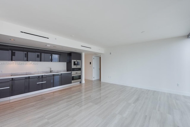 unfurnished living room with light wood-type flooring and sink