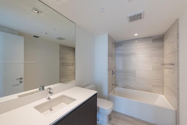 full bathroom featuring vanity, tiled shower / bath combo, hardwood / wood-style flooring, and toilet