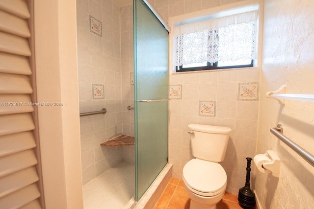 bathroom with tile patterned flooring, toilet, walk in shower, and tile walls