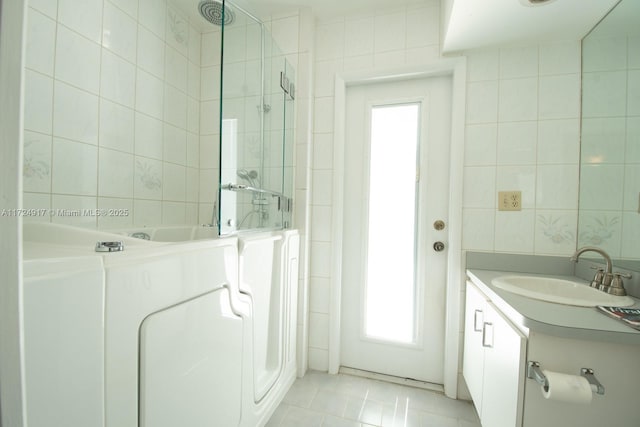 bathroom with vanity, a shower, tile patterned flooring, tile walls, and washer / dryer