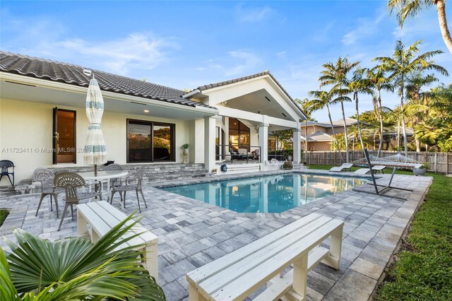 pool at dusk featuring a patio area and pool water feature