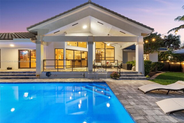 back house at dusk featuring a yard and a patio area