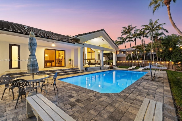 pool at dusk featuring a patio area