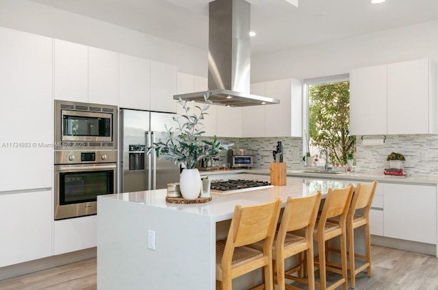 kitchen featuring a kitchen island, white cabinets, appliances with stainless steel finishes, and island exhaust hood