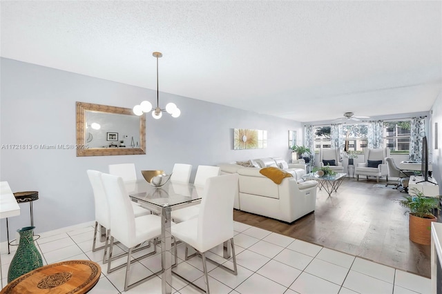 tiled dining room with a textured ceiling and ceiling fan with notable chandelier