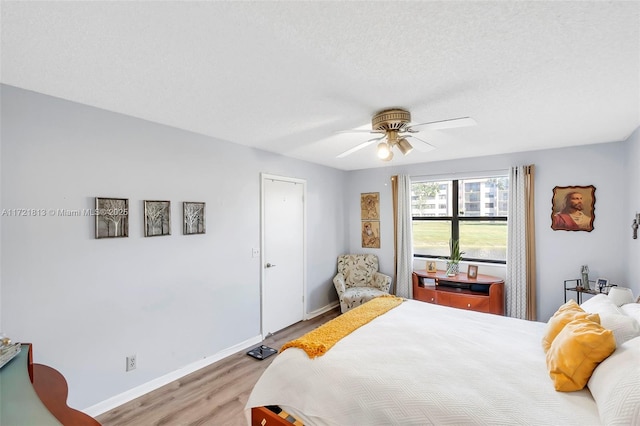 bedroom with ceiling fan, a textured ceiling, and hardwood / wood-style flooring