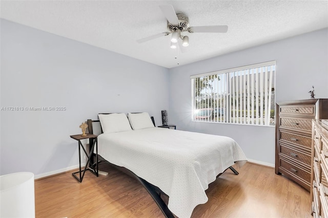 bedroom with a textured ceiling, light hardwood / wood-style flooring, and ceiling fan