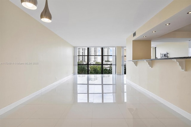 unfurnished room featuring a wall of windows and light tile patterned floors