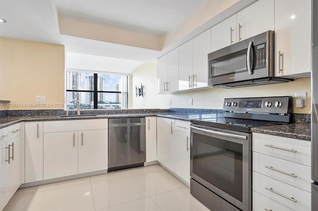 kitchen featuring light tile patterned flooring, sink, white cabinets, dark stone counters, and stainless steel appliances