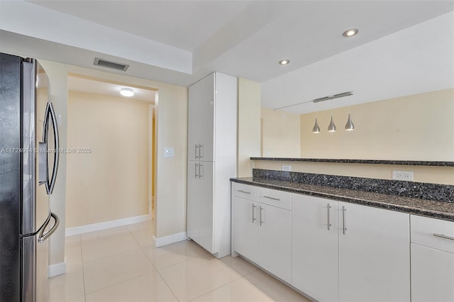 kitchen with decorative light fixtures, white cabinets, stainless steel fridge, and dark stone countertops