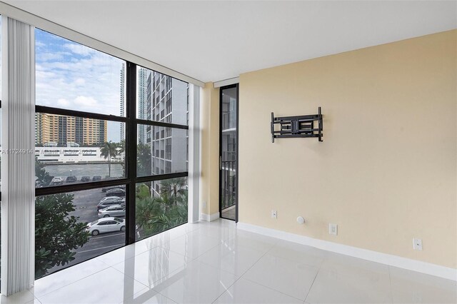 empty room with floor to ceiling windows and light tile patterned flooring