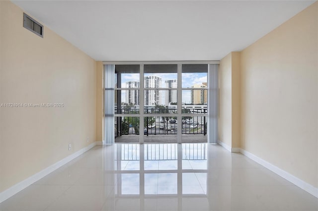 tiled spare room with a wall of windows