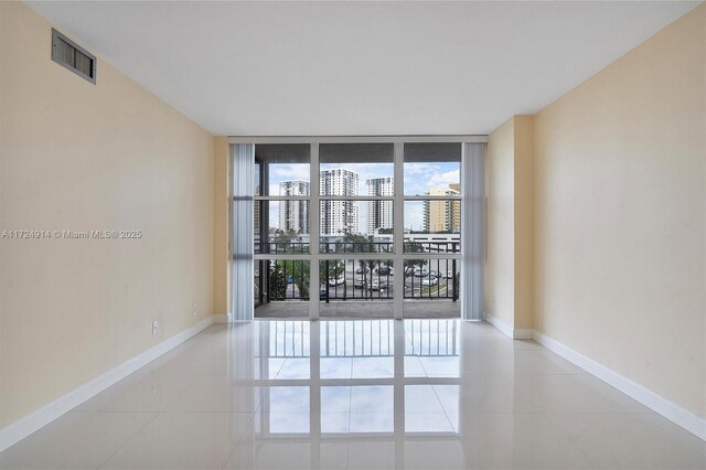 empty room featuring floor to ceiling windows and light tile patterned flooring