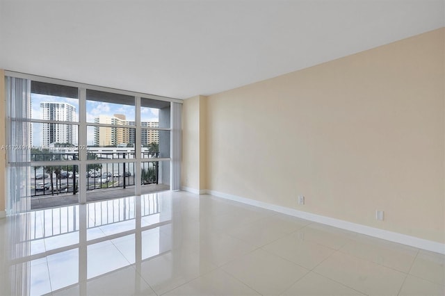 empty room featuring a wall of windows and light tile patterned floors