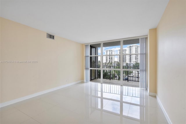 unfurnished room featuring a wall of windows and light tile patterned floors